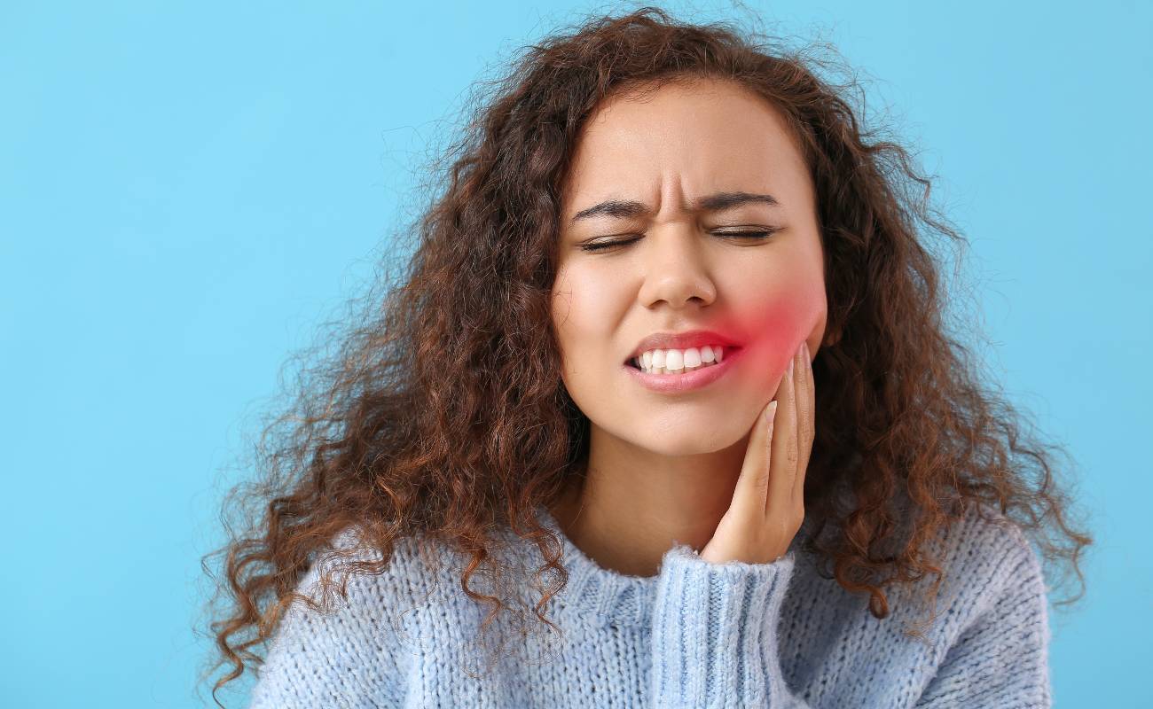 Babské rady na oteklé dásně: Jak zmírnit bolest a zánět v ústech 1 a person holding their jaw in pain, showing swollen and red gums indicative of possible gum inflammation or infection.