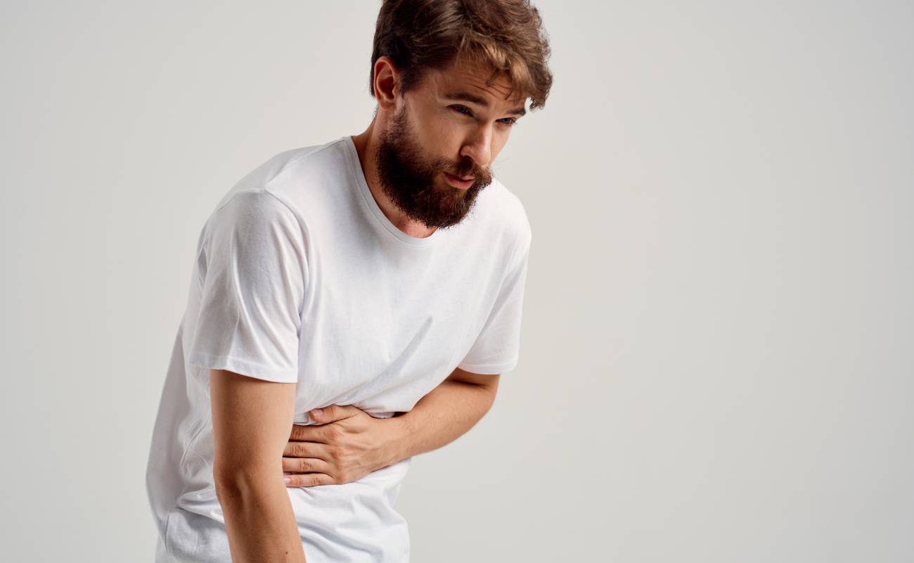 Babské rady na zácpu: 17 Způsobů jak přirozeně zlepšit trávení 1 a man holding his stomach in discomfort, possibly indicating digestive issues like constipation.