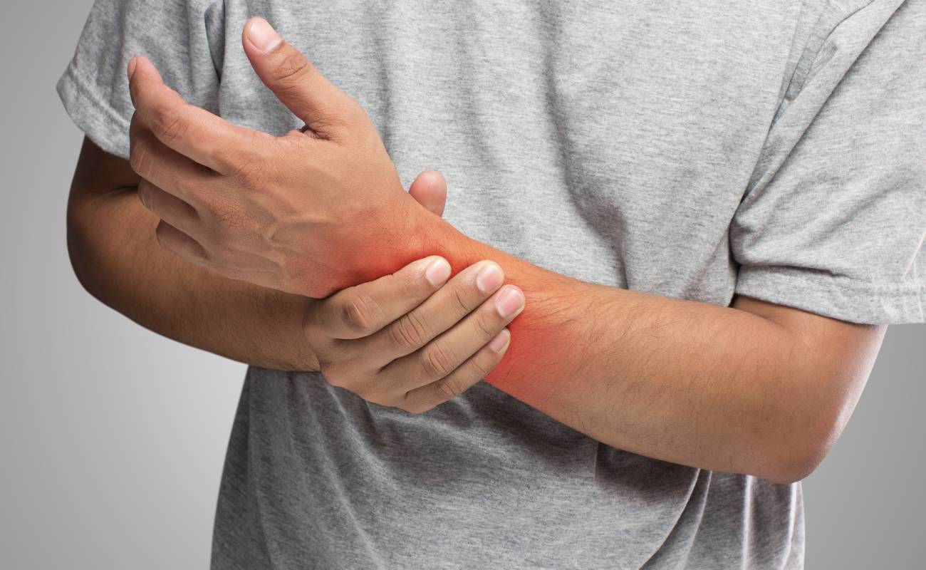 Babské rady na zánět šlach: 9 Přírodních přípravků, které zaručeně pomohou 1 a person holding their painful, inflamed wrist area near the elbow, indicating tendonitis or joint pain.