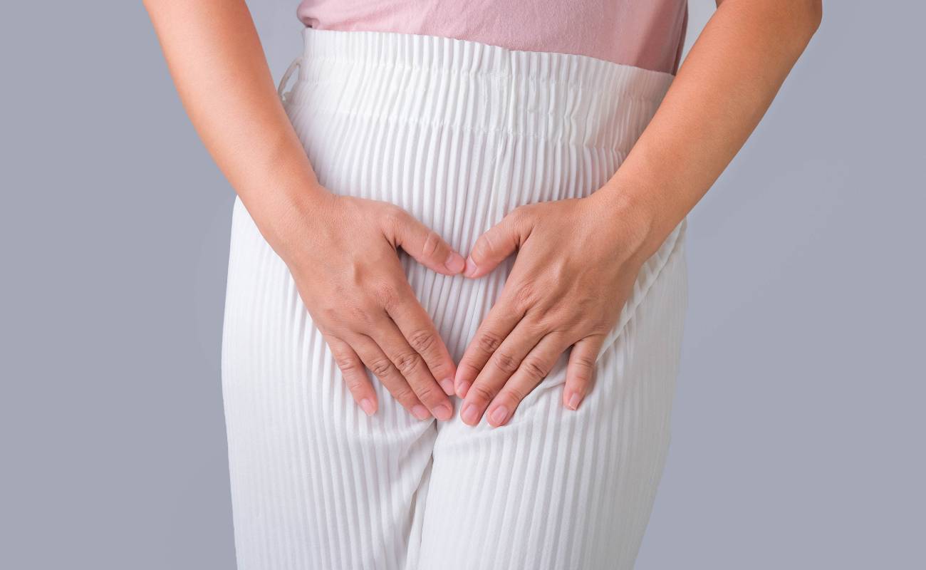 a person holding their hands over the lower abdomen area indicating discomfort related to vaginal itching