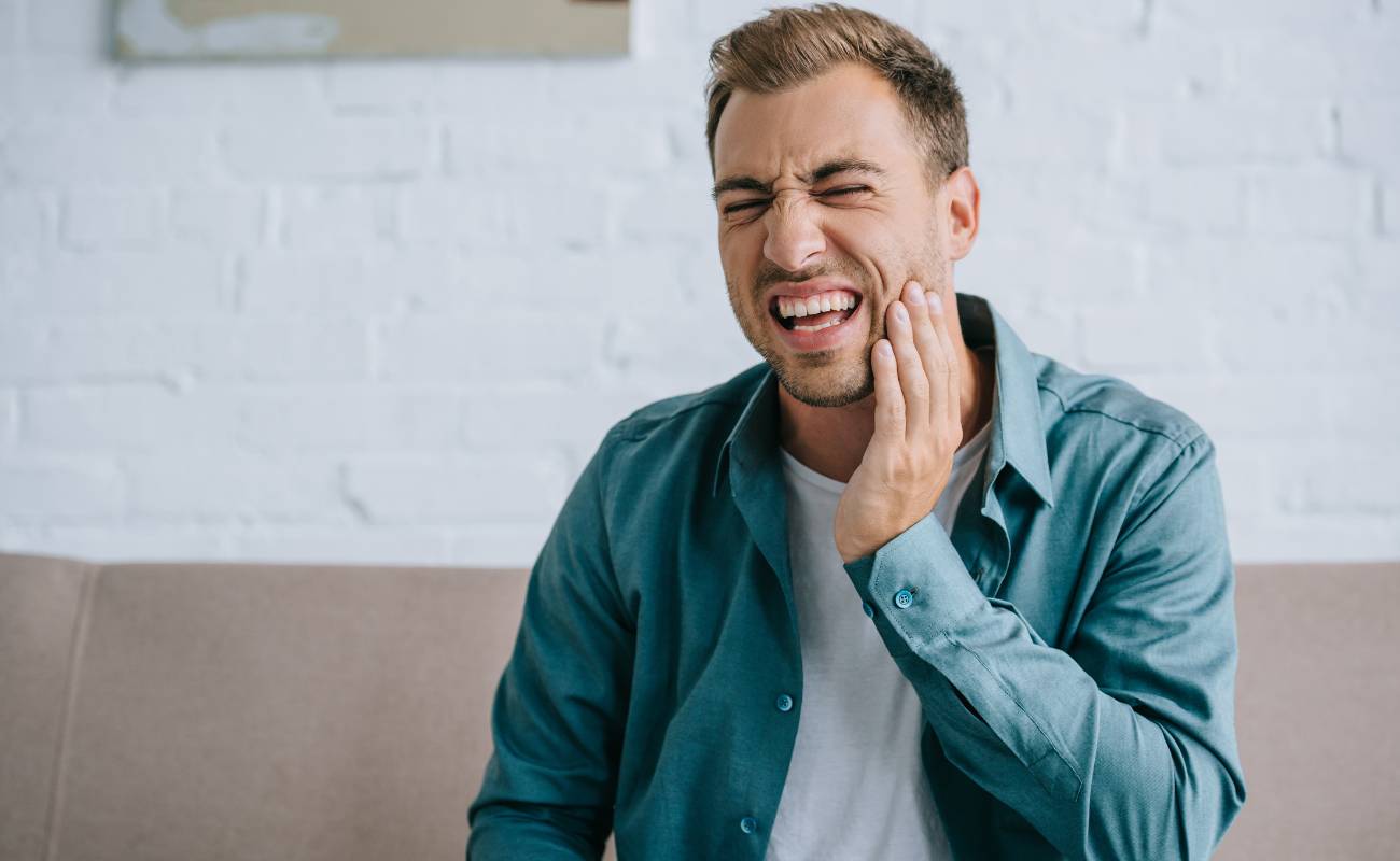 a man holding his jaw in pain, likely illustrating discomfort after tooth extraction, demonstrating post-extraction care concerns