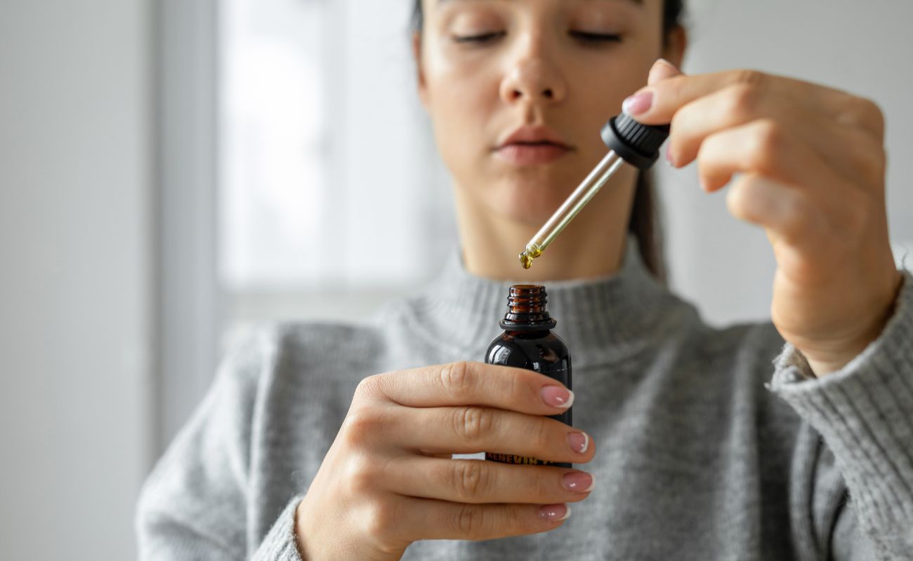 Jsou Lipozomální Vitamíny A Minerály Opravdu Lepší? 5 Hlavních Benefitů Lipozomů 4 a person administering a liquid supplement dropper under the tongue, highlighting sublingual absorption for enhanced nutrient uptake