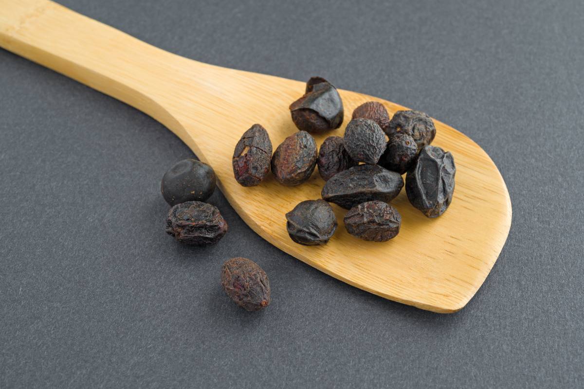 Saw Palmetto: Přírodní Zázrak pro Vaše Zdraví a Prostatu 1 dried saw palmetto berries on a wooden spoon, showcasing Serenoa repens fruit